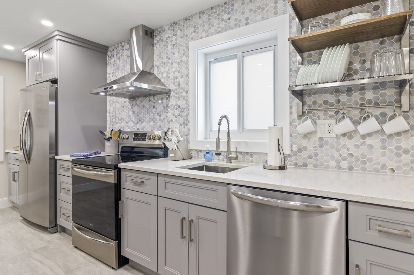 Renovated kitchen with stainless appliances and tile backsplash