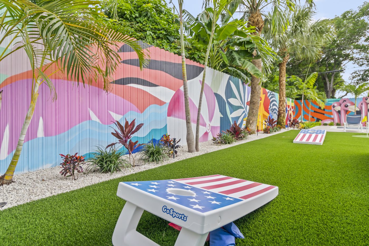 Cornhole board on the turf against the pink mural panel