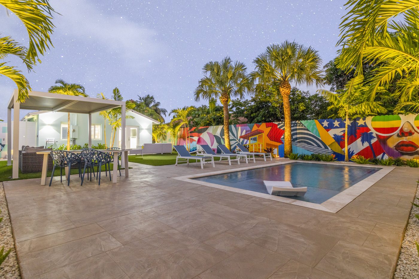 Pool, pergola and mural wall under an evening sky