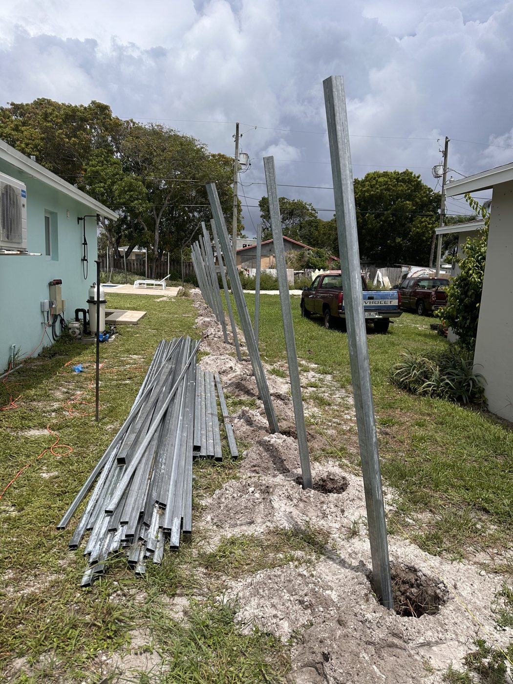 Metal posts set and rails staged in the yard before fence framing