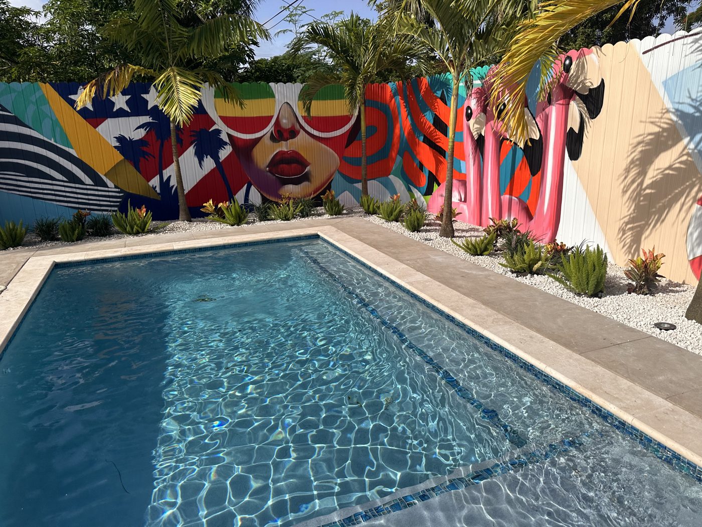 Finished pool with travertine coping under the mural wall