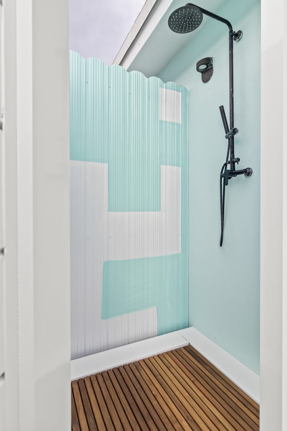 Outdoor shower with teal corrugated panels and a teak floor