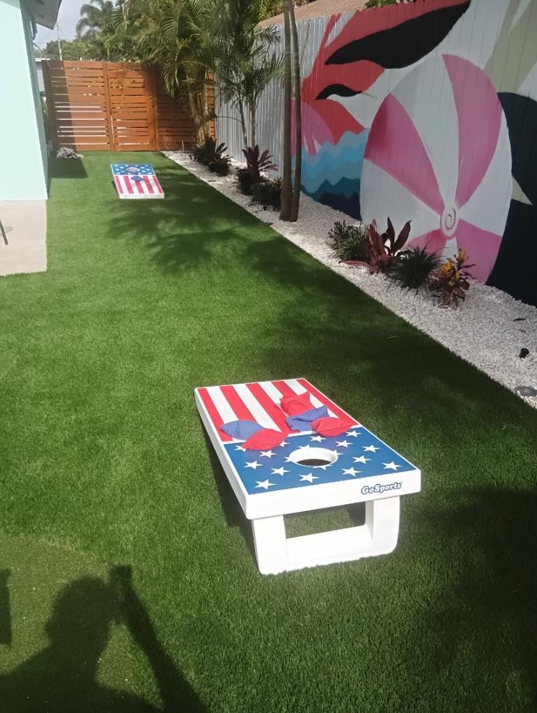 Turf side yard with a cornhole board and mural