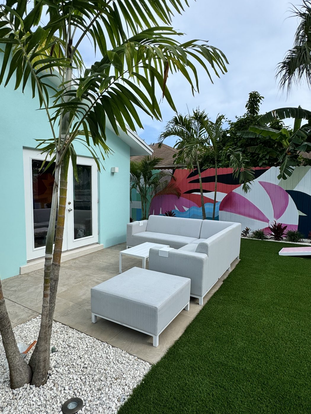 Patio seating under the palms beside the mural