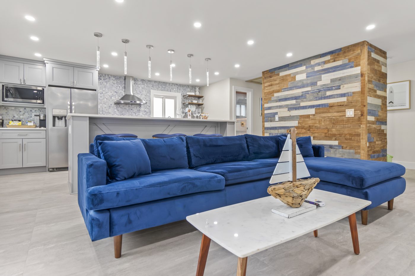 Open kitchen and living room with a blue sectional and stone accent wall
