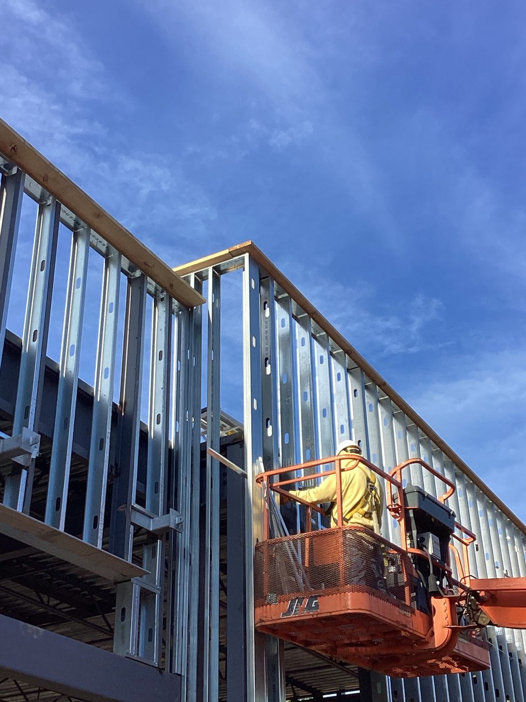 Boom lift at the roofline as the metal roof deck goes on