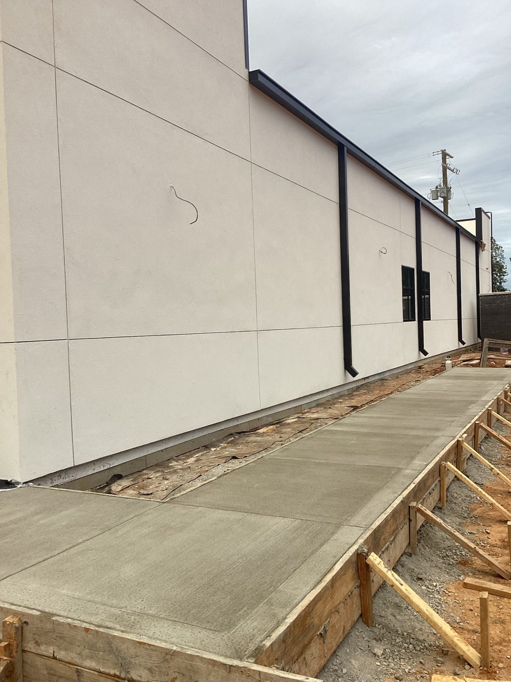 White exterior panels along the side elevation with the new concrete apron