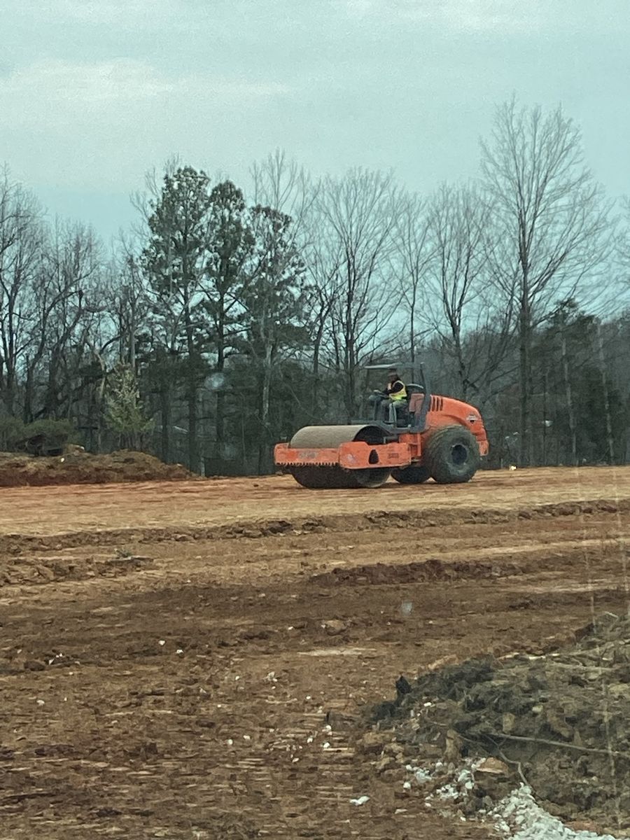 Roller compacting the graded pad