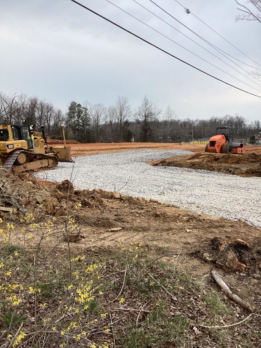 Stone base spread along the site drive, dozer in the background