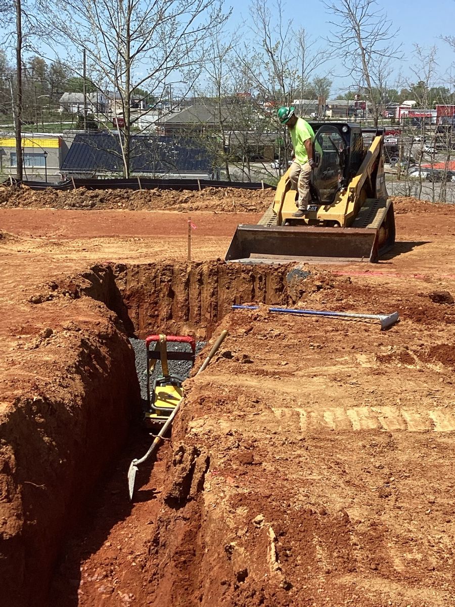 Skid steer beside an open utility trench