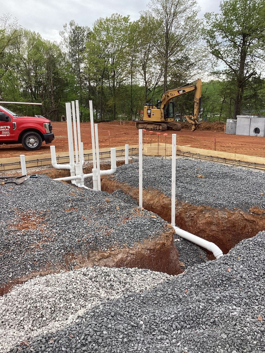 Plumbing stub-ups rising out of the gravel pad
