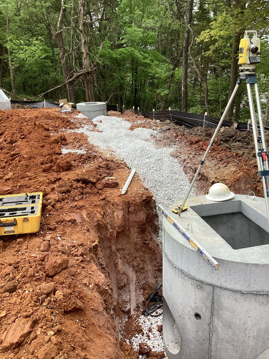 Precast manhole set in the trench with the survey instrument behind