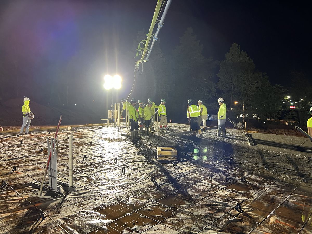 Night slab pour under work lights, crew placing concrete