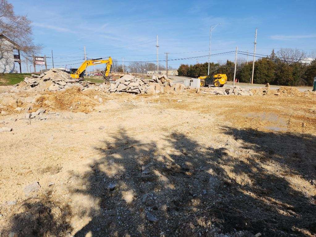Excavator clearing demolition rubble from the old restaurant site