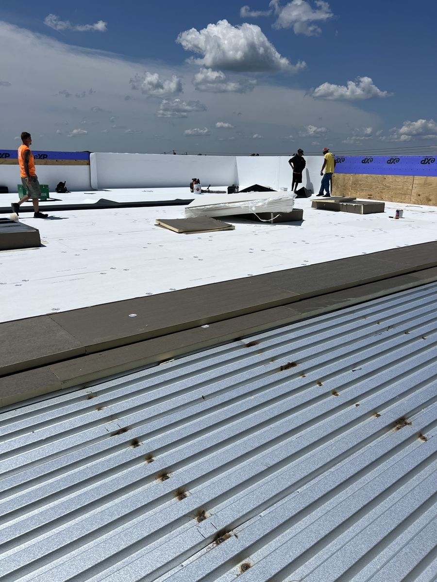 Roofing crew laying cover board and white TPO membrane