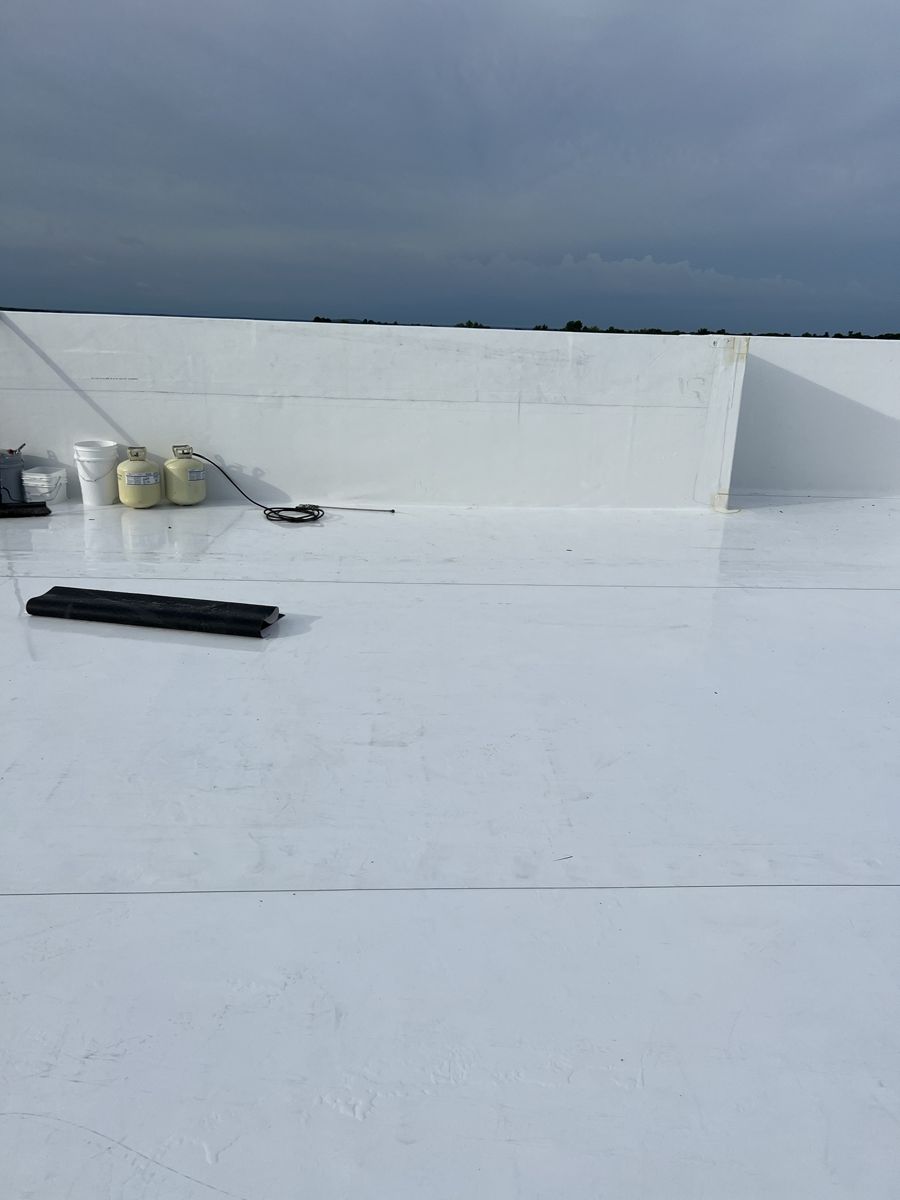 Finished white TPO roof and parapet under a storm sky