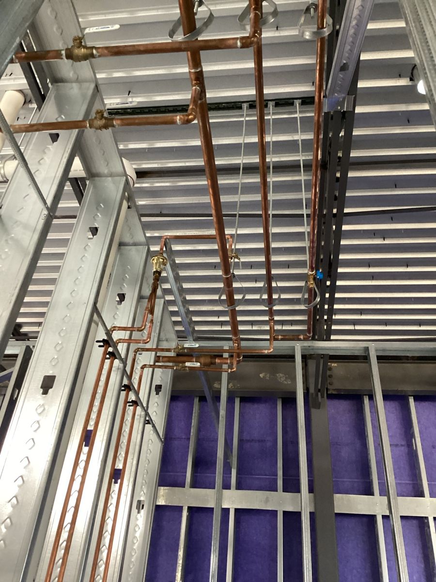 Copper water lines routed through the ceiling framing