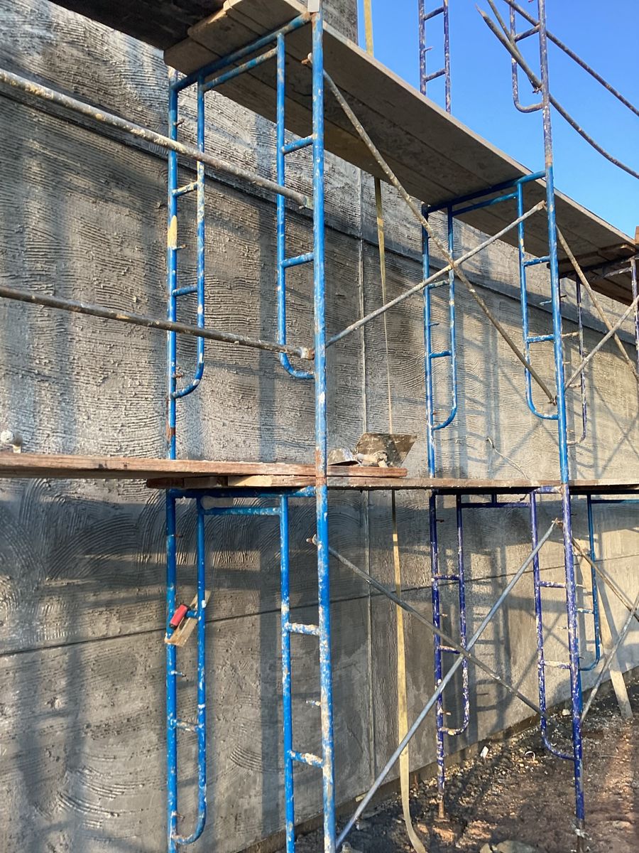 Textured stucco base coat curing behind scaffolding